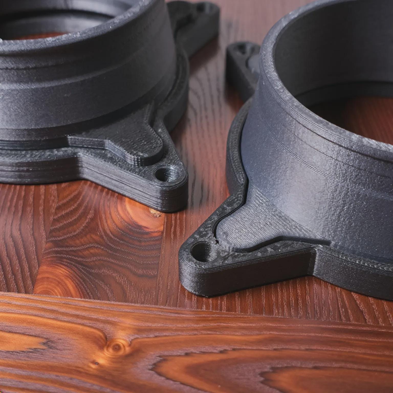 Close-up view of Vent Link through-hull adapter components resting on a wood surface, highlighting precision 3D-printed carbon fiber reinforced polycarbonate construction, clean layer lines, reinforced mounting tabs, and consistent wall thickness. This image emphasizes build quality, durability, and dimensional accuracy for diesel heater airflow systems.