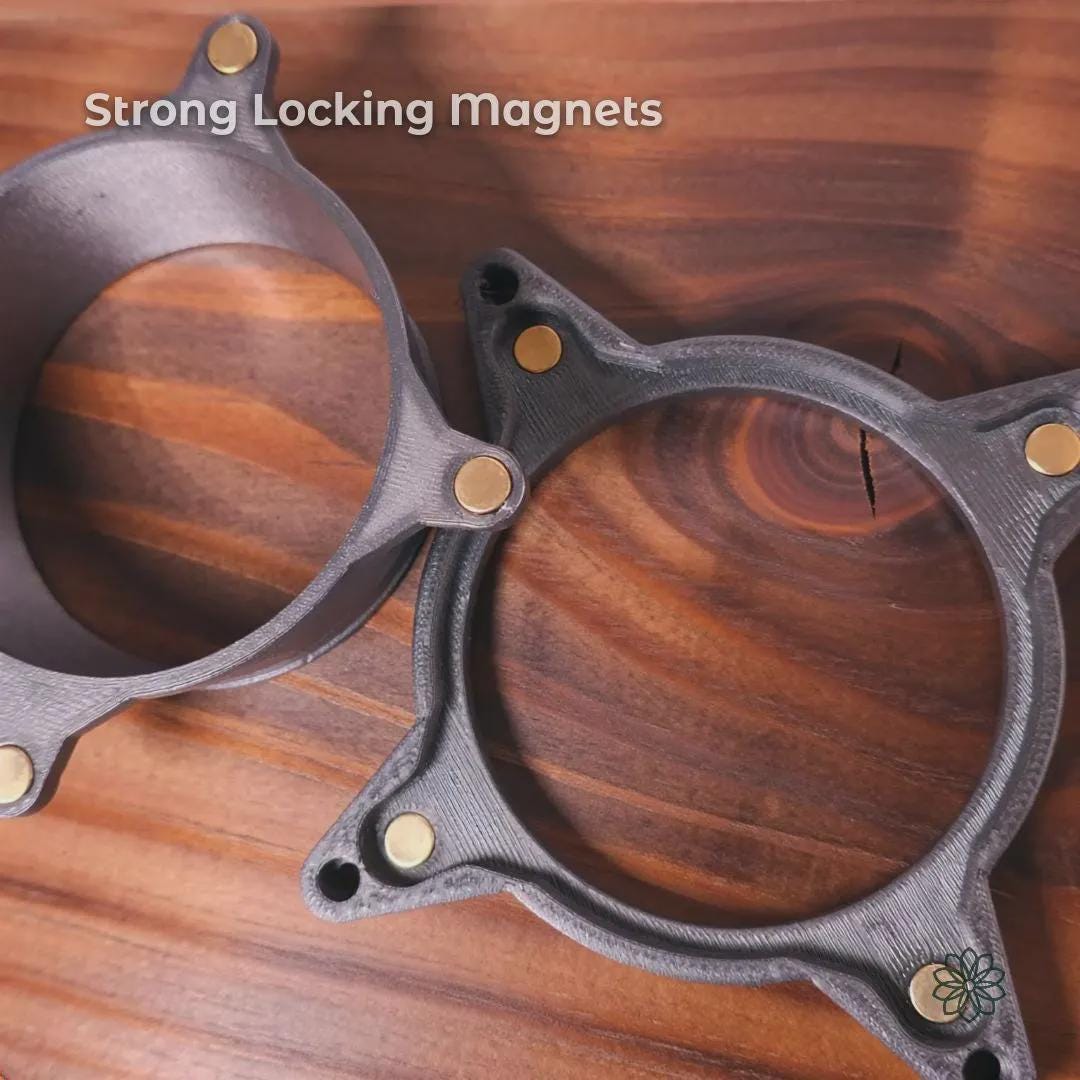 Two Vent Link magnetic coupling rings shown side by side on a wood surface, highlighting embedded locking magnets used to maintain alignment and secure airflow connections. The carbon fiber reinforced polycarbonate rings demonstrate the magnetic interface that allows fast attachment and removal while resisting vibration and airflow movement. On-image text reads “Strong Locking Magnets.