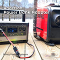 Outdoor winter scene showing a portable lithium power station on a wooden surface connected to a red diesel air heater using an Anderson Power Bank Adapter cable. The image includes the text “Anderson Power Bank Adapter” and “Daisy Power Systems.” The adapter converts a 12-volt cigarette lighter output from the power bank to Anderson Powerpole connectors for off-grid heater use.