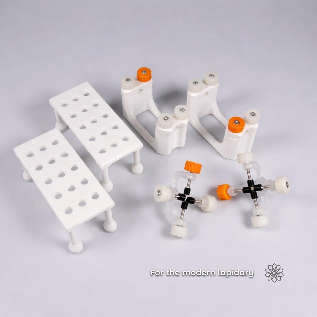 Studio photo showing multiple Aetherium lapidary tools arranged on a neutral background, with on-image text reading “For the modern lapidary.” White modular fixtures, adjustment knobs, and hardware are displayed together to represent a coordinated tool ecosystem designed for organized, repeatable lapidary workflows.