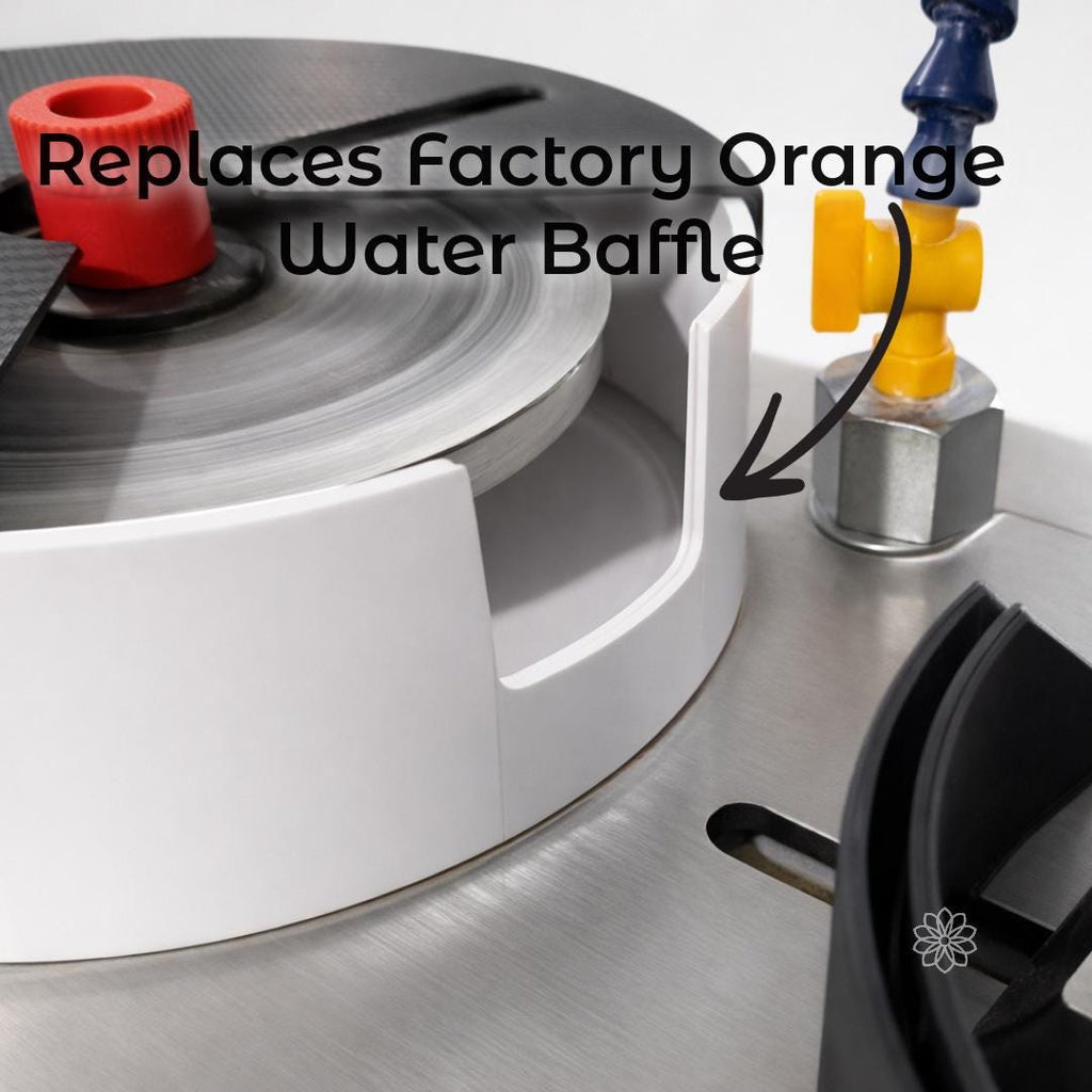 Close-up of a Vevor faceting machine basin showing the upgraded black water baffle installed in the original factory position, with on-image text reading “Replaces Factory Orange Water Baffle.” An arrow points to the baffle location near the coolant outlet, indicating this component replaces the original orange water deflector to restore water control.