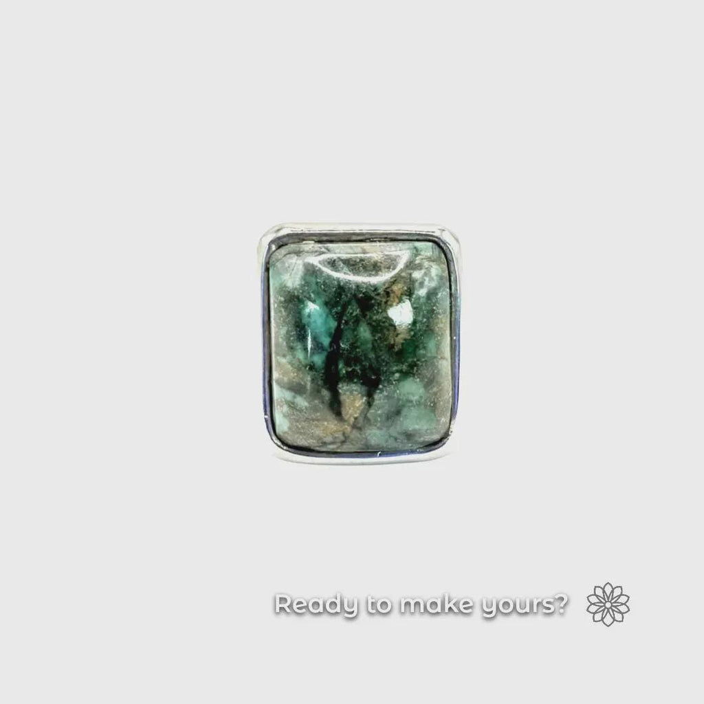Macro photo of a finished square cabochon ring with a polished green-blue stone in silver bezel. Clean lines and mirror finish emphasize craftsmanship possible from PolyCast digital ring blank designs.