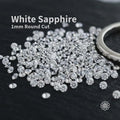 White sapphire gemstones, 1 mm round cut, loose accent stones displayed on dark velvet fabric, bright clear sparkle with uniform size, ideal for pavé settings, halo rings, and fine jewelry embellishment.