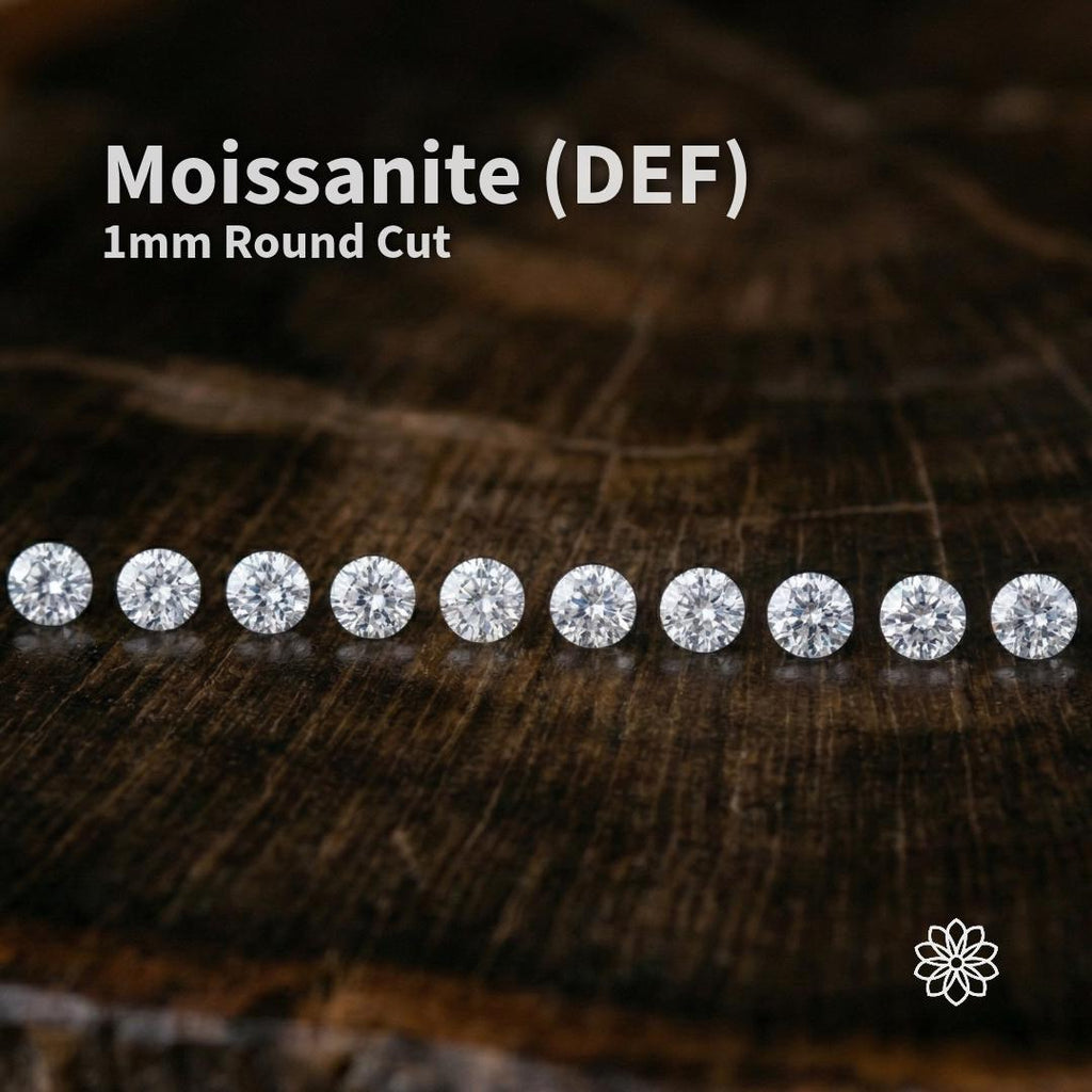 Hero image of DEF color 1 mm round cut moissanite stones arranged in a straight line on a dark wood background. The calibrated micro gemstones show bright white brilliance, high fire, and diamond-like sparkle for pavé and halo jewelry settings. Overlay text reads “Moissanite (DEF) 1mm Round Cut.” A small Aetherium floral logo appears in the lower corner.
