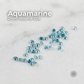 Hero image of 2 mm round cut lab-grown aquamarine stones scattered on a light neutral surface. The gemstones show soft light blue color with clean clarity and subtle brilliance. Overlay text reads “Aquamarine 2mm Round Cut.” Stones appear calibrated and consistent for jewelry making, micro pavé, and accent stone settings. A small Aetherium logo is visible in the corner.