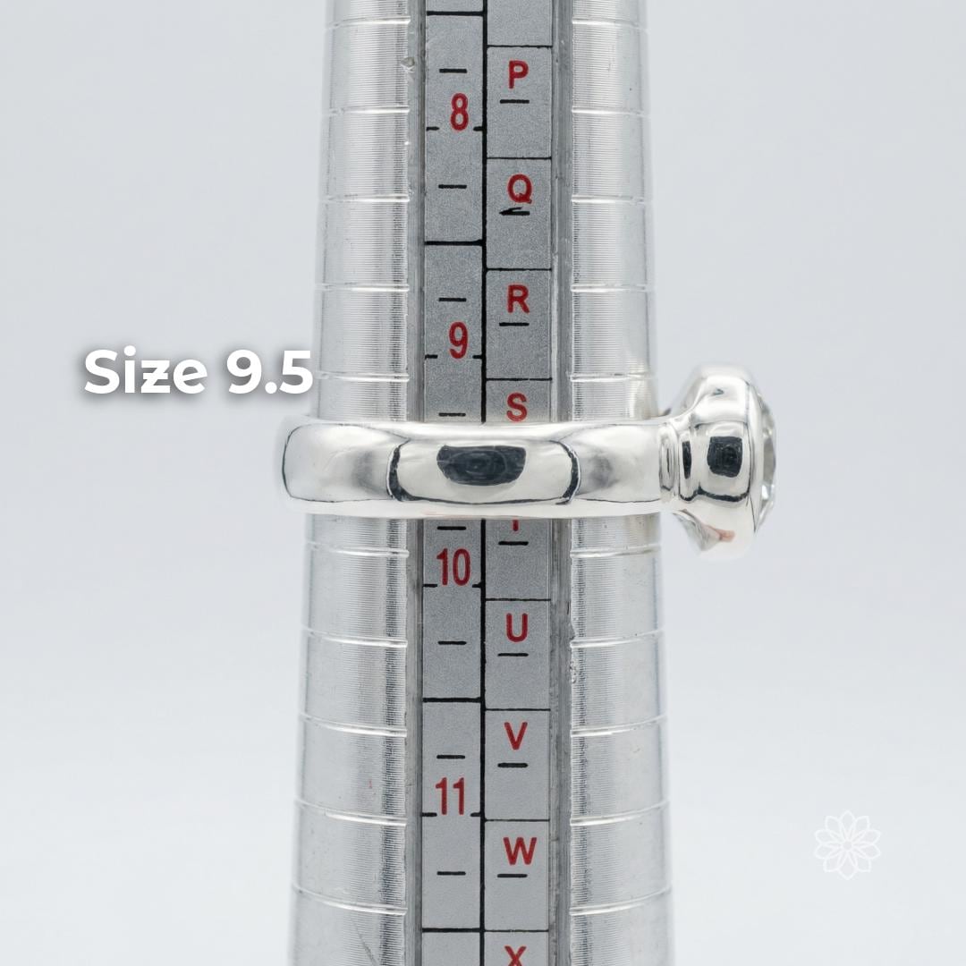Side profile of a sterling silver bezel-set moissanite ring on a metal ring mandrel showing the band shape, low setting height, and scale. The ring is displayed at size 9.5. Visible text says “Size 9.5.”