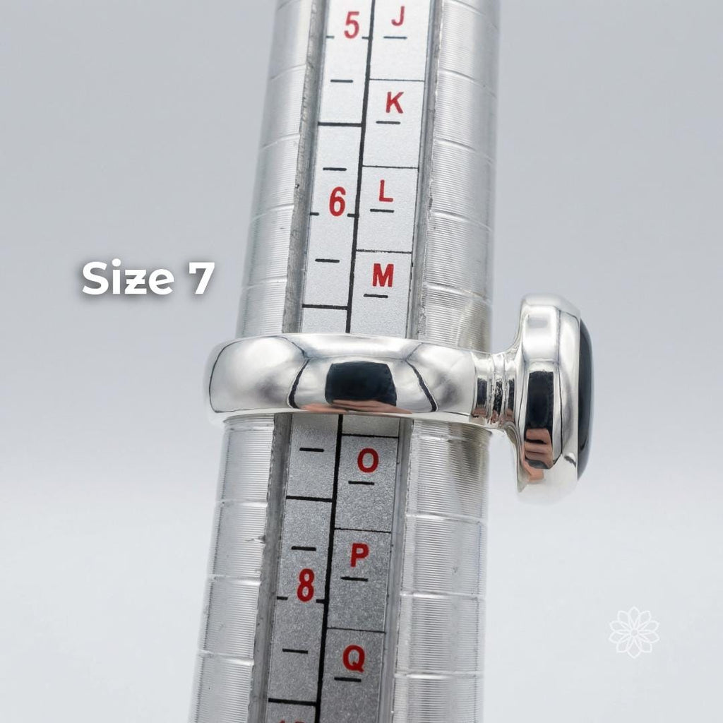 Side view of a sterling silver sapphire cabochon ring on a ring mandrel showing band thickness and bezel height, labeled size 7. Text reads “Size 7.”