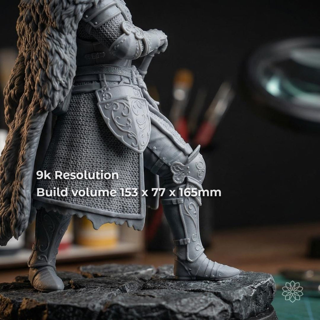 Close-up of a highly detailed gray resin figurine showing fine textures, armor detail, and smooth surface finish. Overlay text indicates 9K resolution and compact build volume, reinforcing high pixel density and precision capability for small, complex parts requiring accurate detail reproduction.