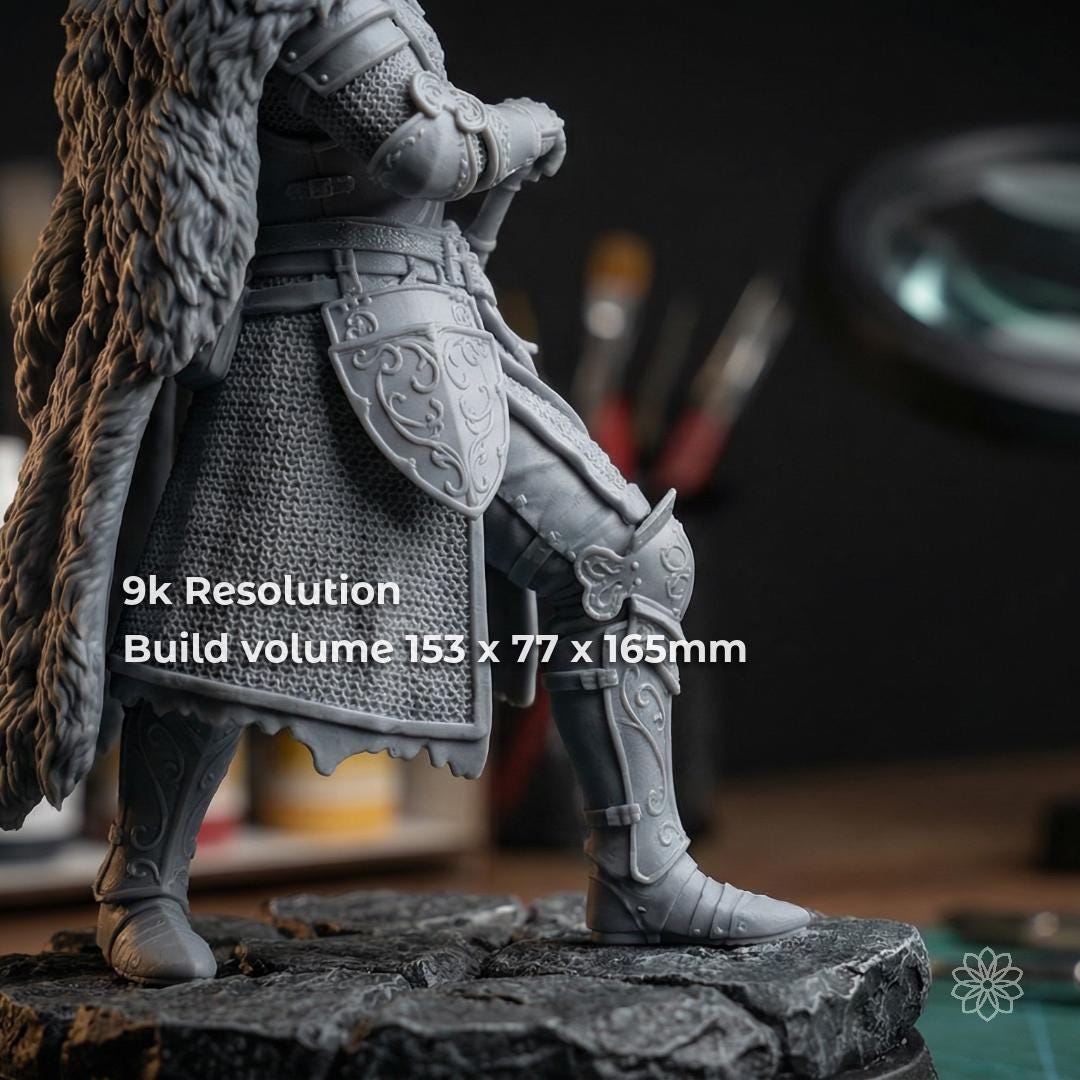 Close-up of a highly detailed gray resin figurine showing fine textures, armor detail, and smooth surface finish. Overlay text indicates 9K resolution and compact build volume, reinforcing high pixel density and precision capability for small, complex parts requiring accurate detail reproduction.