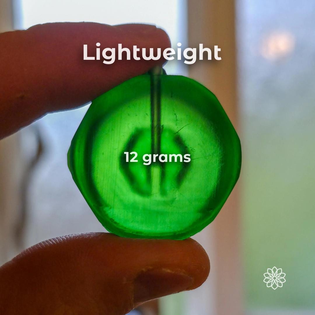 Ultralight green bottle bidet cap held between fingers showing compact size and 12 gram weight. Lightweight backpacking hygiene tool designed to minimize pack weight while providing controlled water flow for cleaning and rinsing in outdoor environments.