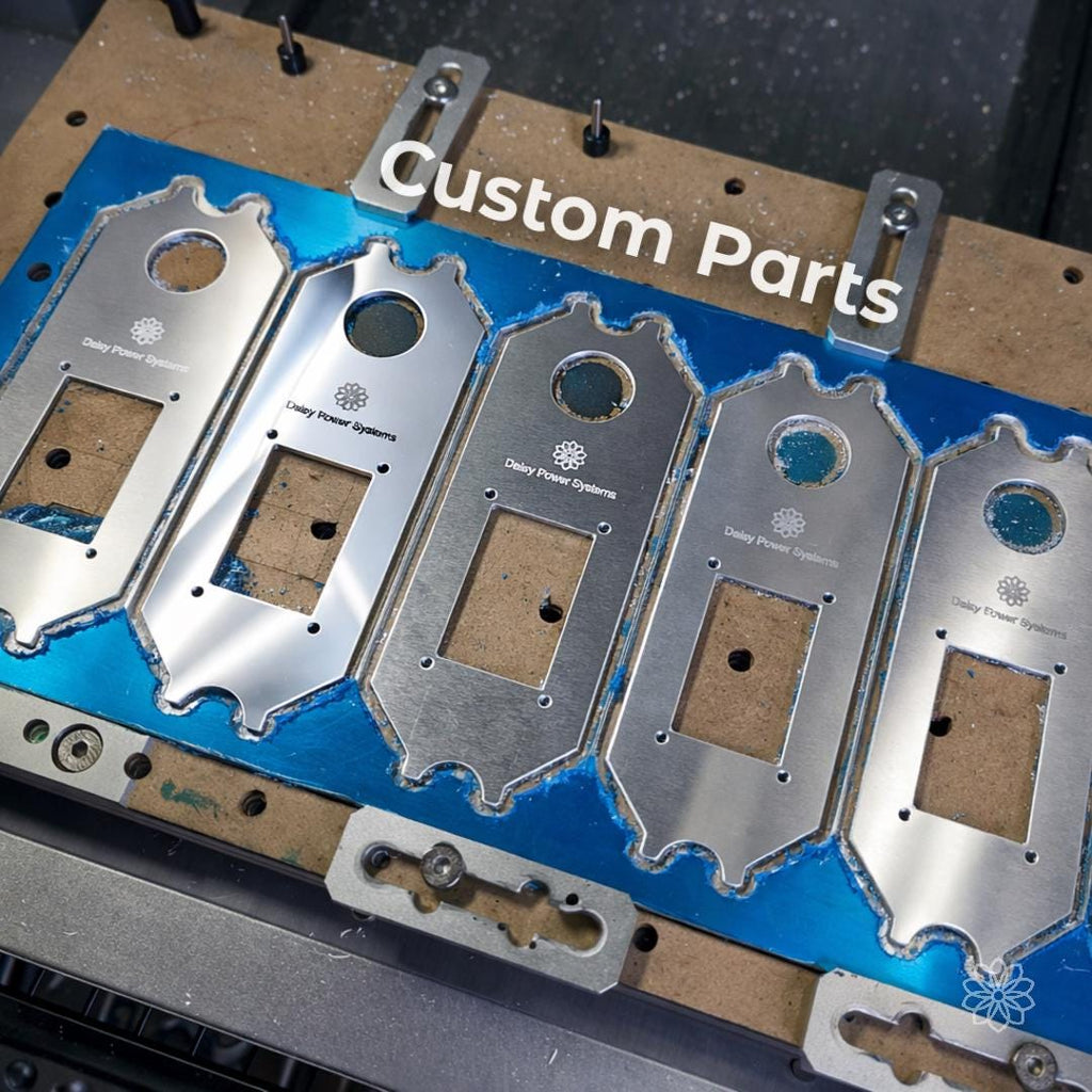 Batch of machined aluminum plates mounted on CNC bed with consistent cut quality and repeatable geometry. Overlay text reads “Custom Parts.” Clean edges, uniform hole placement, and identical profiles demonstrate small batch production, fixture-based machining, and repeatability for functional components and product manufacturing.