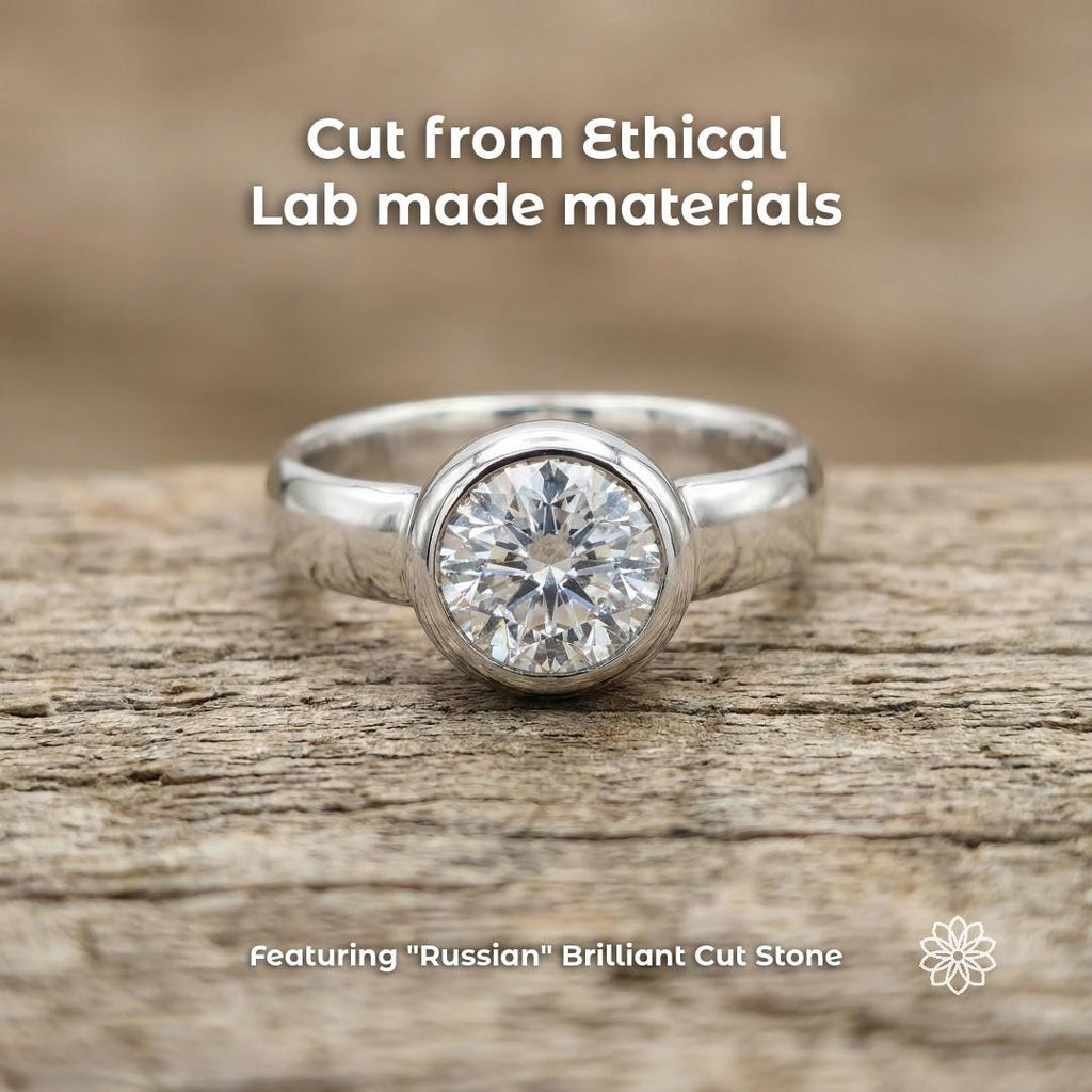 3ct round brilliant moissanite ring set in sterling silver bezel, displayed on textured wood surface. Lab-grown gemstone with high clarity and strong light reflection. Clean silver band and centered stone emphasize symmetry, sparkle, and precision cut, photographed in soft natural lighting.