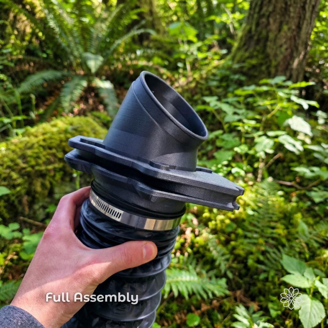 Full Tent Link heater port assembly held by hand with flexible duct attached, showing complete diesel heater airflow system with angled adapter and main housing, black carbon fiber composite components used for directing heat into rooftop or ground tents.
