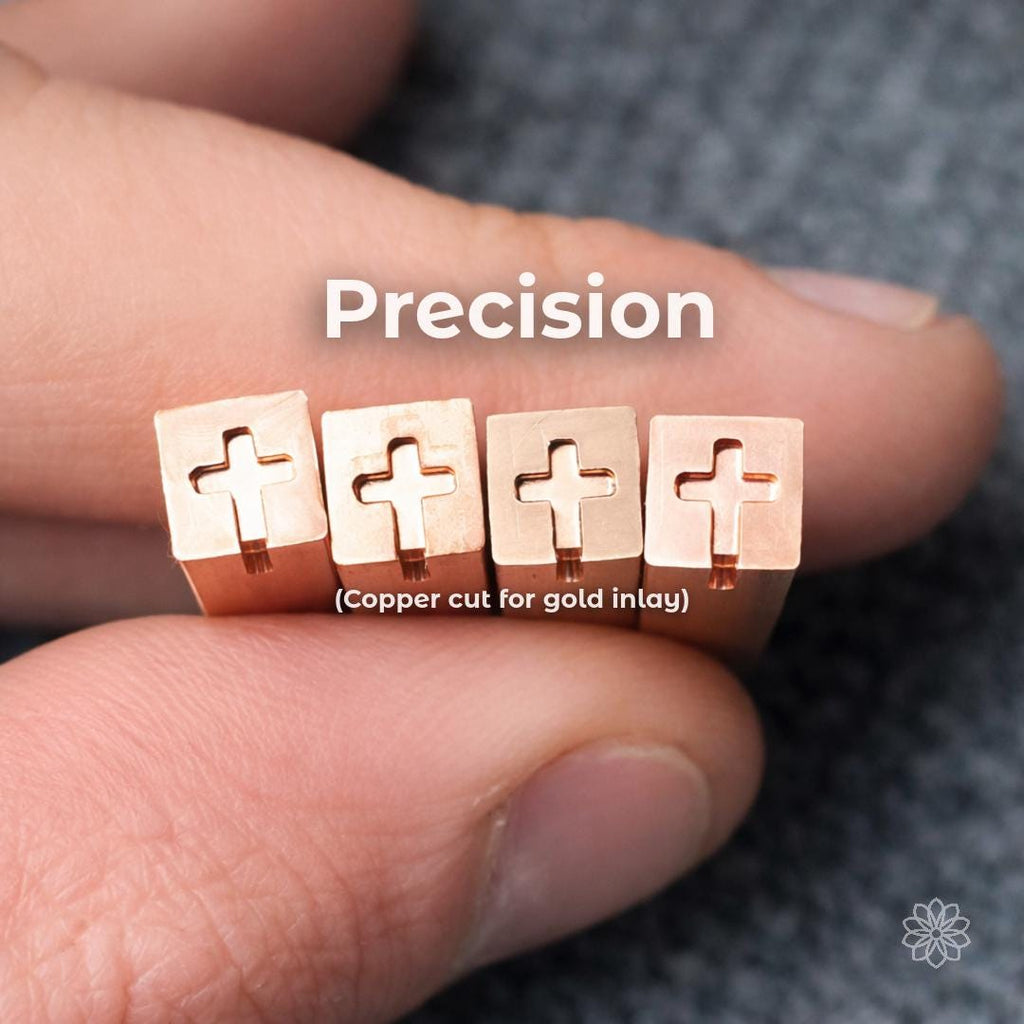 Close-up of small copper blocks held between fingers, each with a precisely machined cross-shaped cavity. Overlay text reads “Precision (Copper cut for gold inlay).” Sharp internal corners and consistent depth show high-accuracy machining suitable for fine detail work, inlay preparation, and jewelry-scale components.