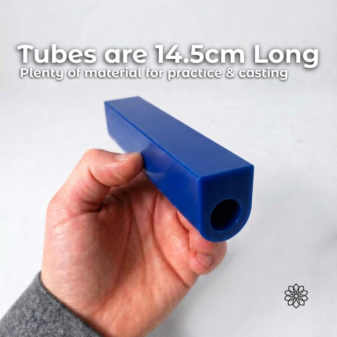Hand holding a long blue jewelry carving wax ring tube with a centered ring hole and flat-sided profile used for lost wax casting, ring carving, signet ring making, CNC jewelry machining, and rotary tool carving. The image shows the physical size and usable carving stock. Text reads “Tubes are 14.5cm Long” and “Plenty of material for practice & casting.” Aetherium flower logo appears at lower right.