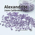 Lab-grown alexandrite gemstones, 1 mm round brilliant cut, shown loose on a white studio surface with additional stones stored in a clear glass jar. Stones display muted lavender to gray-green tones typical of synthetic alexandrite under neutral lighting. Consistent size and cut geometry intended for precision bench setting, pavé layouts, and fine jewelry or inlay work.
