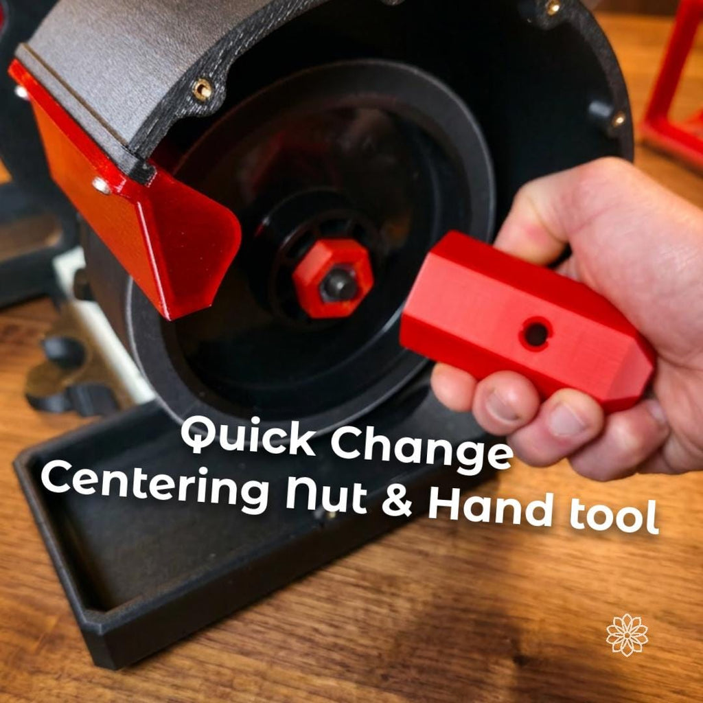 Hand holding the red quick-change centering nut and hand tool in front of the Cut n’ Cab V2 MakerSpace Edition grinder housing, showing tool-free style setup support for fast accessory changes on the modular workstation.