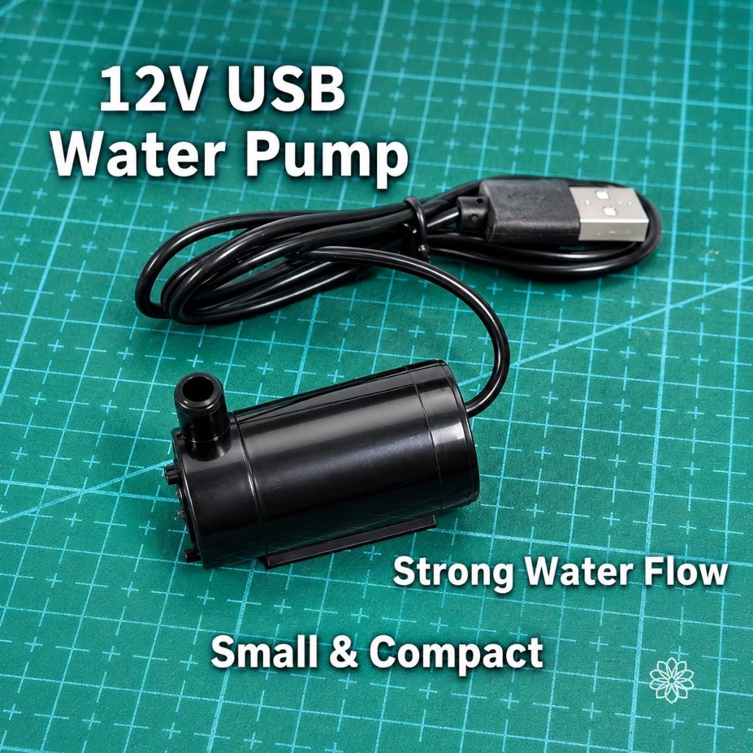 Compact 12V USB water pump for the Cut n’ Cab V2 MakerSpace Edition shown on a green cutting mat, with USB power cable and small pump body for active water cooling during wet cutting, grinding, and abrasive maker workflows.