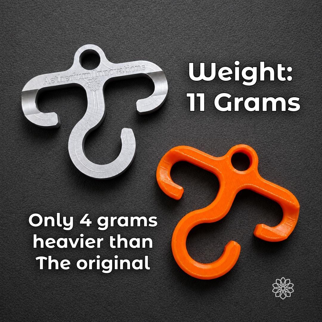 Weight comparison showing the machined aluminum Paracord Hook Mini at 11 grams beside the original orange plastic version, only 4 grams heavier. Built for EDC carry, backpacking, hiking, and camping users who want a stronger metal gear hook without adding unnecessary bulk.