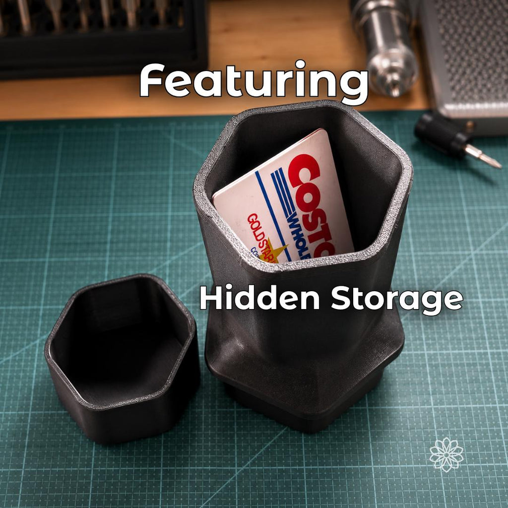 Black Jeep Nalgene cup holder adapter shown on a workbench with the lower storage compartment open, demonstrating integrated space for cards, passes, cash, or small personal items beneath the bottle holder.