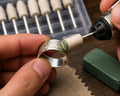 Hands using a rotary tool fitted with a felt polishing bob charged with polishing compound to refine an engraved silver ring. Close-up jewelry finishing workflow showing detail polishing in tight areas where larger buffing wheels cannot reach. Hard felt polishing point with 2.35mm shank used for jewelry making, metal finishing, engraving, restoration, lapidary work, and precision polishing applications.