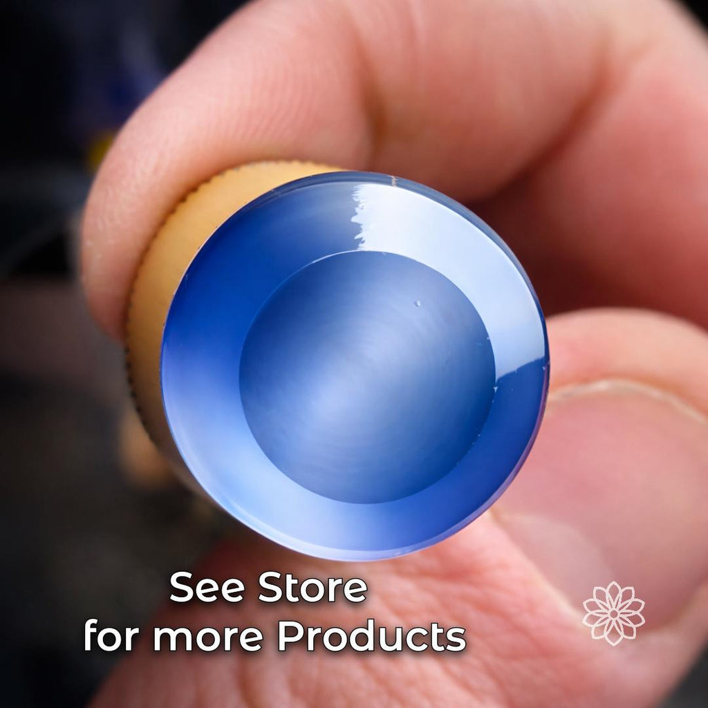 Polished blue cabochon gemstone held by hand, showing a smooth domed surface and reflective finish. Example of finished lapidary work made with gemstone cutting, polishing, faceting, cabbing, and precision stone shaping tools.