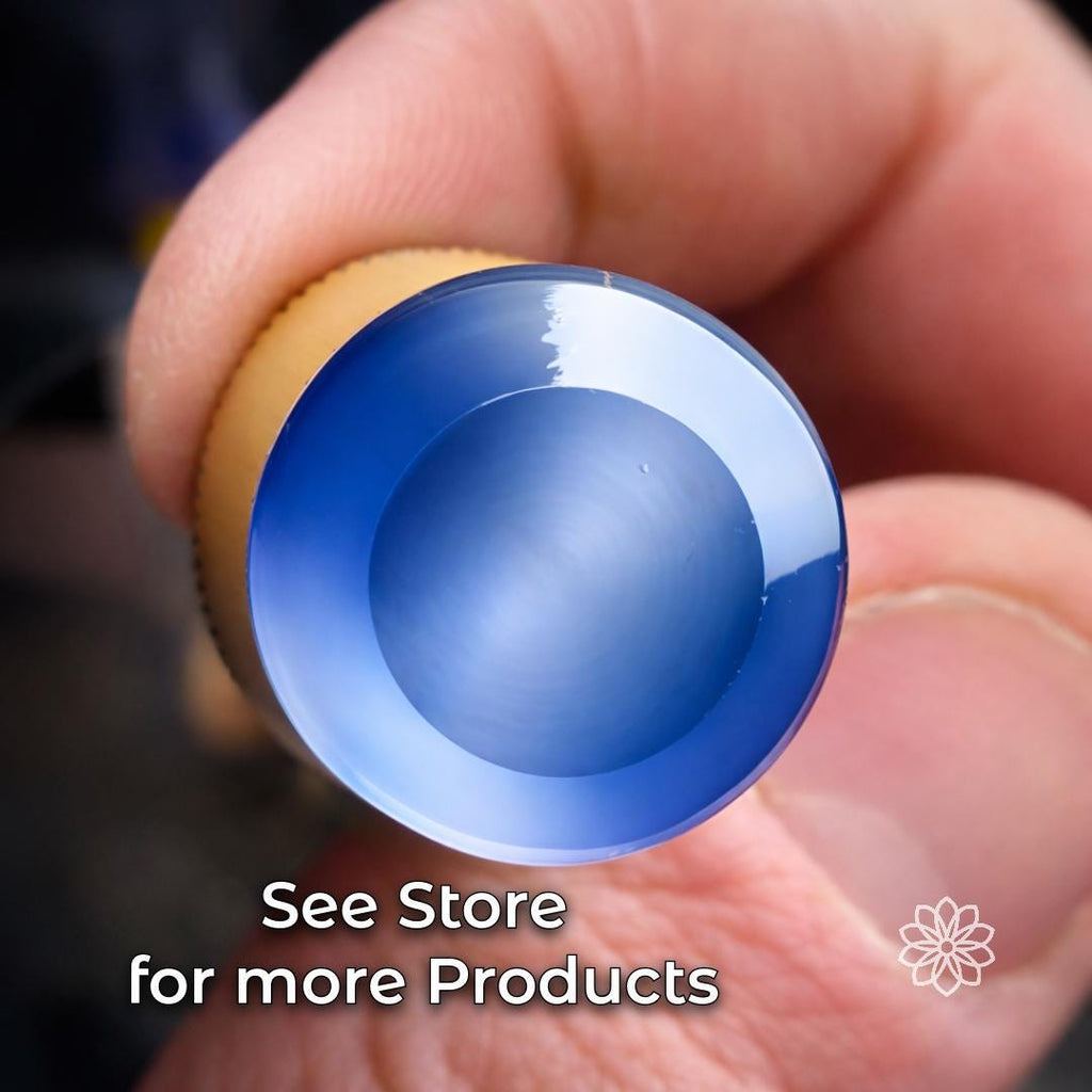 Polished blue cabochon gemstone held by hand, showing a smooth domed surface and reflective finish. Example of finished lapidary work made with gemstone cutting, polishing, faceting, cabbing, and precision stone shaping tools.
