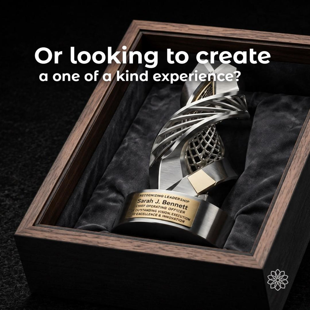 Sculptural silver-and-gold leadership award displayed in a dark walnut presentation case. Overlay asks about creating a one-of-a-kind experience, representing bespoke corporate awards and recognition pieces designed around a recipient, achievement, or company milestone.
