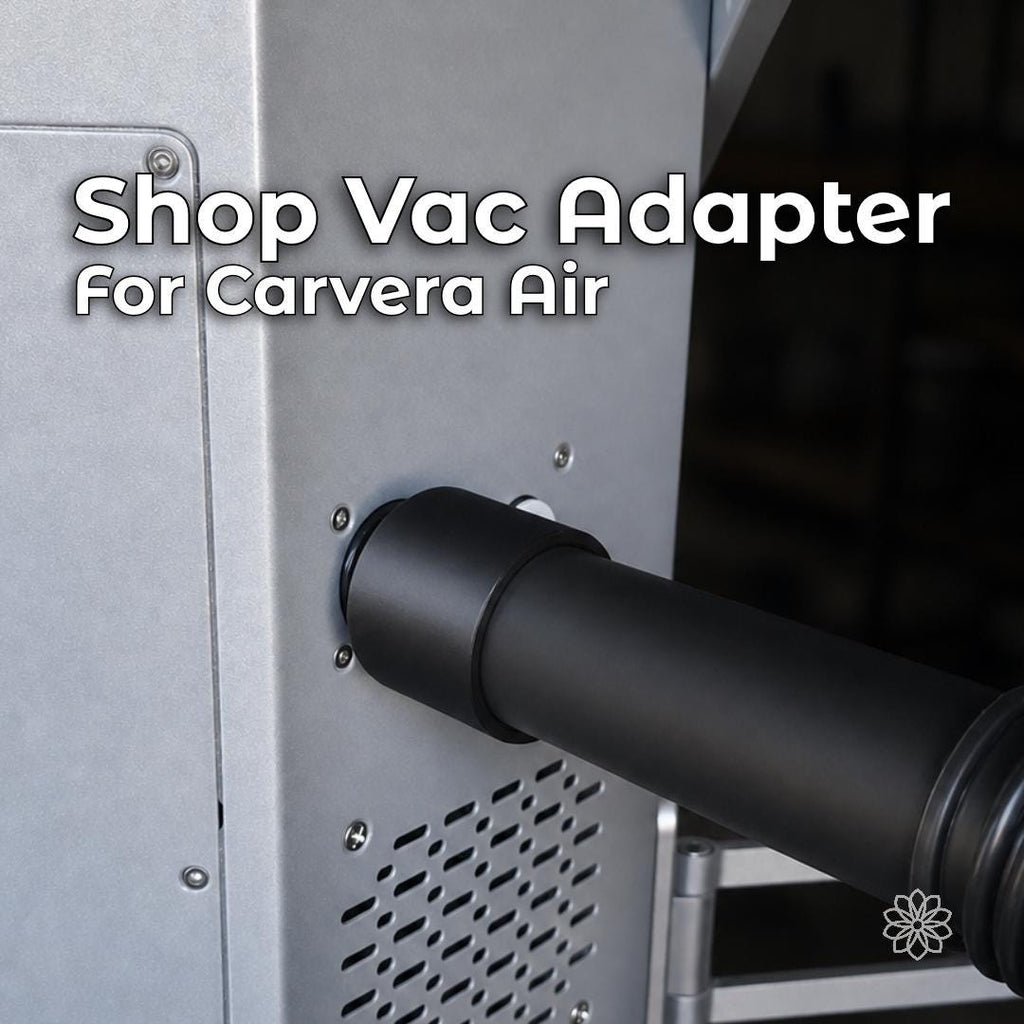 Makera Carvera Air shop-vac adapter with black 3D-printed construction, installed between the desktop CNC machine's rear dust port and a vacuum hose for external chip and dust collection.