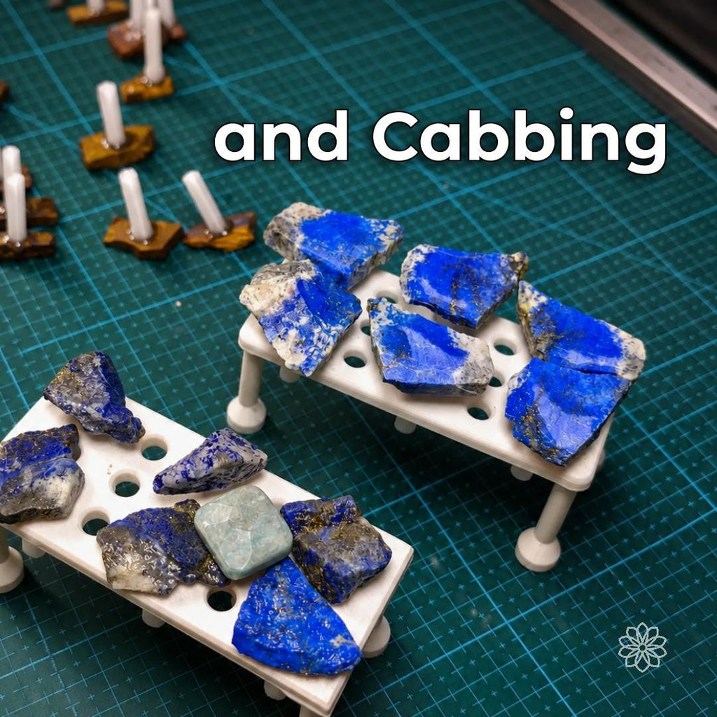 Multiple blue lapis lazuli cabochons and rough stone preforms arranged on white lapidary dop stands, with several stones already bonded to dops in the background. The image shows the dop system supporting batch cabochon shaping and polishing workflows.