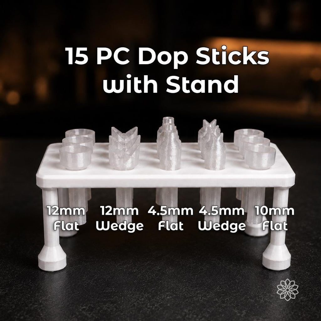 White dop stick stand holding fifteen clear polycarbonate 6 mm lapidary dop sticks in five included profiles: 12 mm flat, 12 mm wedge, 4.5 mm flat, 4.5 mm wedge, and 10 mm flat. The organized assortment supports gemstone faceting, cabochon work, adhesive dopping, transfers, and multiple stones in progress.
