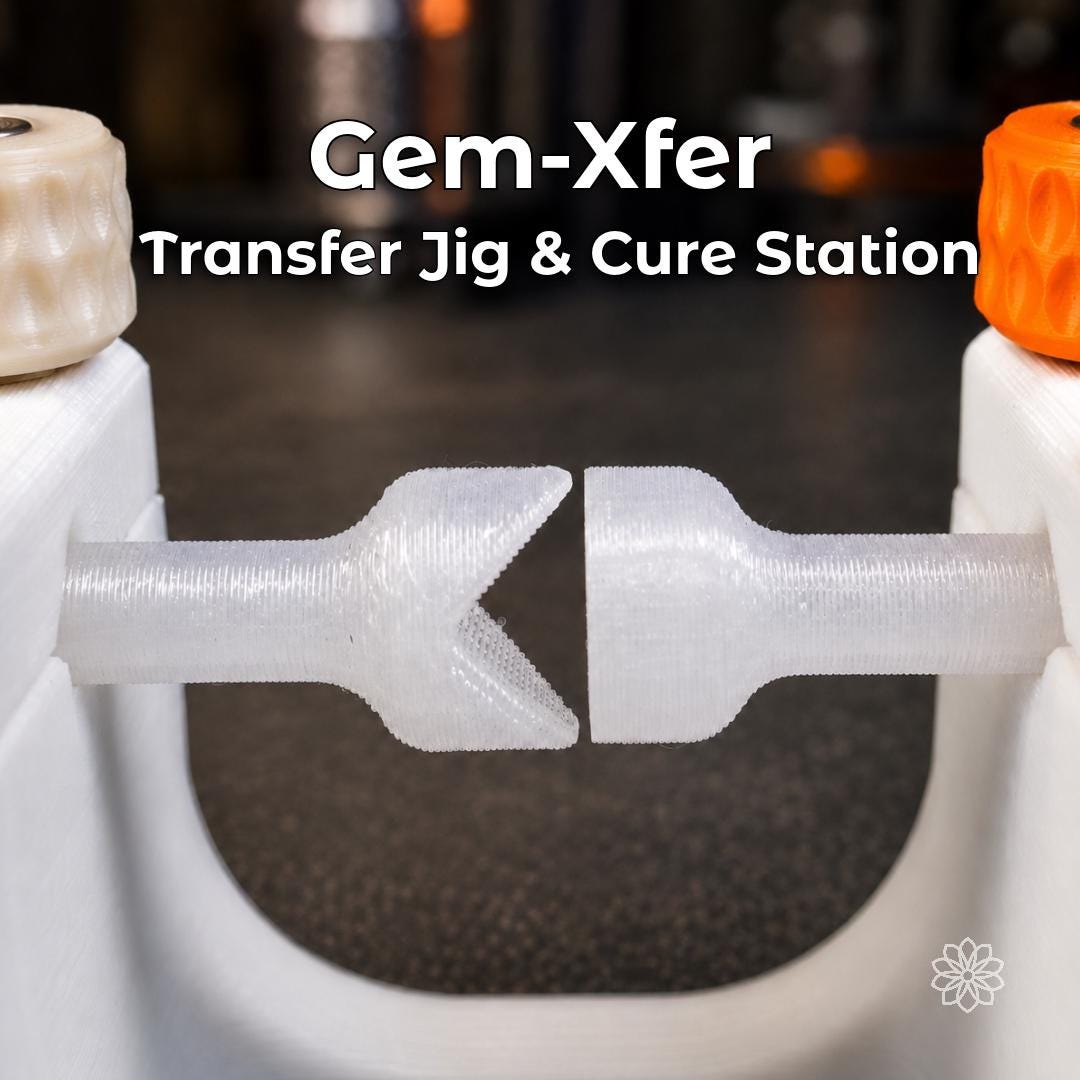 Close-up of the Aetherium Gem Xfer gemstone transfer jig and epoxy cure station with two opposing clear polycarbonate dops aligned inside a white adjustable frame. The 3D-printed lapidary fixture uses metal hardware and orange adjustment knobs to support controlled transfers and stable adhesive curing.