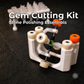Aetherium Gem Cutting Kit displayed on a dark workshop surface, featuring the white Gem Xfer gemstone transfer and epoxy cure station with adjustable metal hardware and orange control knobs. A white dop stand with clear polycarbonate dop sticks appears behind it. The kit supports gemstone dopping, alignment, transfer, curing, and organized faceting workflows.
