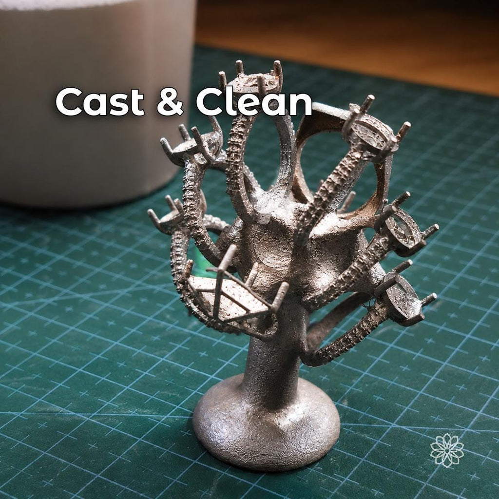 Freshly cast jewelry tree with multiple ring settings and small components still attached to the central sprue after lost wax casting. Image shows the metal casting stage before sprue removal, cleanup, finishing, polishing, and stone setting.